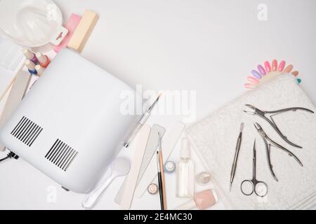 Maniküre und Pediküre Artikel - Nagellack Trocknungslampe, Nagelfeile, Scheren und Bürsten über hellen Hintergrund Stockfoto