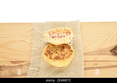 Zwei duftende Käsekuchen mit appetitanregenden Geschmack liegen auf einer Stoffserviette auf einer hölzernen Tischplatte. Der Hintergrund ist weiß. Stockfoto