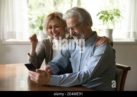 Überglücklich reifes Paar Spaß mit Smartphone zu Hause zusammen Stockfoto