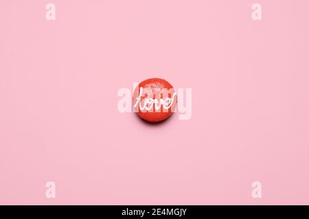 Ein roter Valentinstag Macaron mit dem Wort Liebe geschrieben Darauf mit Glasur auf einem pastellrosa Hintergrund mit Platz und Platz für Text kopieren Stockfoto