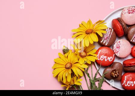 Verschiedene Tagestarone auf pastellrosa Hintergrund mit Das Wort Liebe auf sie geschrieben mit Frühling gelb Gänseblümchen Blumen mit Kopierraum und r Stockfoto