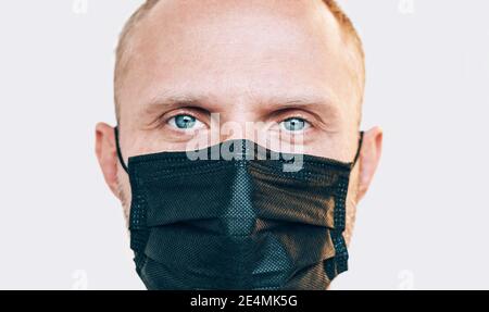 Porträt eines Mannes, der während einer COVID-19-Weltpandemie eine schwarze Gesichtsmaske verwendet und die Kamera anschaut. Selbstschutz und Virenausbreitung zu stoppen Maßnahmen concep Stockfoto
