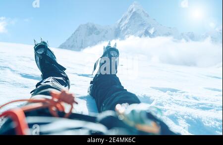 POV schießen eines Höhenbergsteigers die Lags in Steigeisen. Er liegt und ruht auf Schnee-Eis-Feld mit Ama Dablam (6812m) Gipfel mit c bedeckt Stockfoto