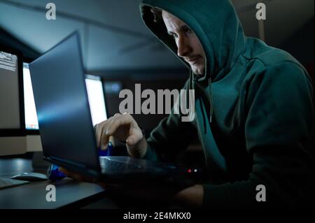 Männliche Internet-Hacker in Haube arbeitet auf Laptop Stockfoto