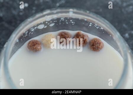Glas Milch mit Getreidekugeln auf Marmorboden Stockfoto