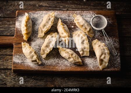 Asiatische rohe Knödel auf Holzschneidebrett. Traditionelle chinesische Dim Sum Knödel. Stockfoto