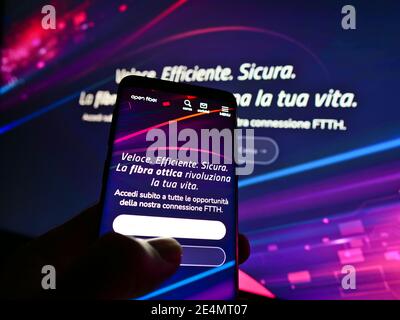 Person hält Smartphone mit Website und Logo der italienischen Telekommunikationsgesellschaft Open Fiber Spa auf dem Display. Fokus auf die Mitte des Bildschirmphones. Stockfoto