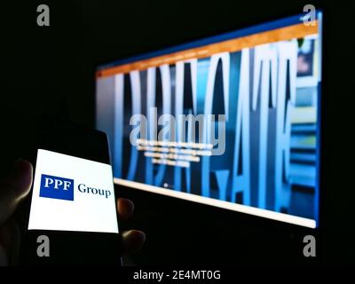 Person hält Telefonbildschirm mit Logo der niederländischen Finanz-und Investmentgesellschaft PPF Group N.V. auf dem Display. Konzentrieren Sie sich auf den Smartphone-Bildschirm. Stockfoto