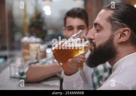 Nahaufnahme eines bärtigen Mannes, der Licht nippt Bier im Pub Stockfoto