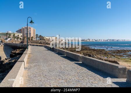 Cadiz, Spanien - 16. Januar 2021: Blick auf die Stadt Cadiz und den Paseo de Fernando Quinones Gehweg am La Caleta Strand Stockfoto