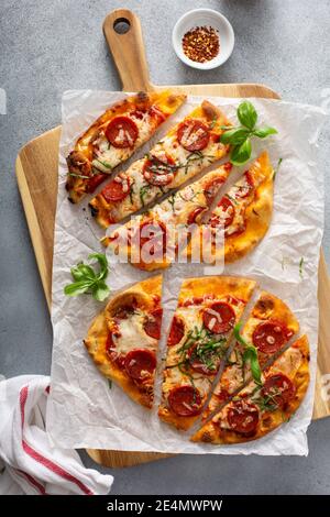 Fladenbrot Pepperoni Pizza mit Basilikum Stockfoto