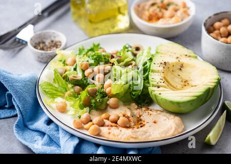 Salatschüssel mit Avocado, Hummus und Grüns. Nahaufnahme. Gesunder veganer Salat Stockfoto