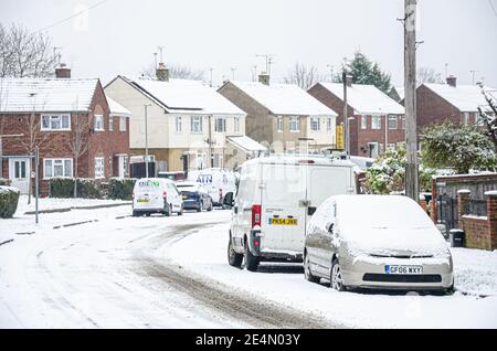 Eine Wohnstraße in Reading, Berkshire, Großbritannien ist mit Schnee bedeckt. Autospuren führen in die Ferne. Stockfoto