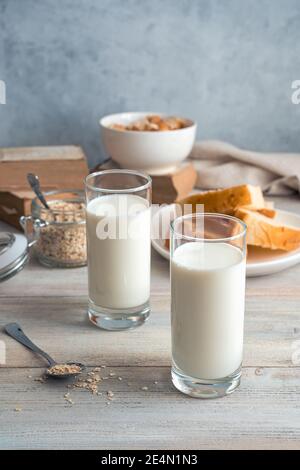 Milch in Gläsern, Haferflocken und Brotflocken auf grauem Hintergrund. Stockfoto