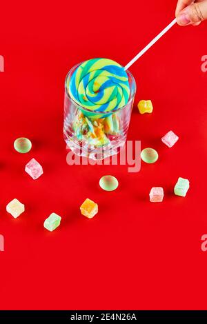 Bunte Lutscher im leeren Glas mit Bonbons auf Rot Hintergrund Stockfoto