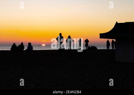 Menschen beobachten den Sonnenuntergang über dem Meer in Brighton, Beach, East Sussex, England, Großbritannien Stockfoto