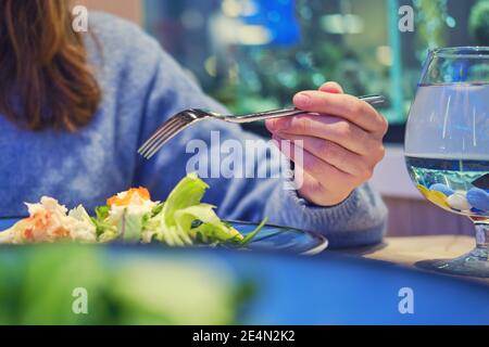 Eine Frau isst in einem Fischrestaurant einen Salat mit Krabbenfleisch und Rucola. Abendessen im Seafood Cafe Stockfoto