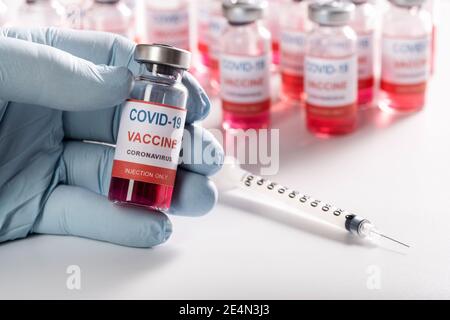 Impfstofffläschchen in der Hand von Ärzten Nahaufnahme, Spritze und viele Glasflaschen Stockfoto