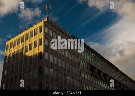 Blick auf das Bürogebäude aus Beton aus den 1960er Jahren des 20. Jahrhunderts. Handy-Mast auf dem Dach. Sonniger Tag mit Schatten werfen. Stockfoto