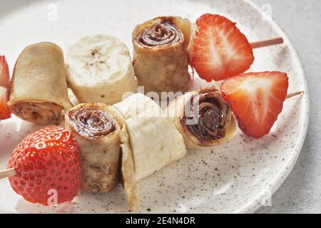 Spieße von Pfannkuchen Crepes mit Nussbutter und Obst Stockfoto