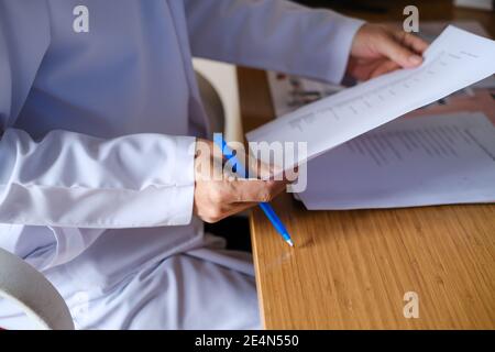 Der Arzt untersucht die Dokumente des Patienten. Seitenansicht des Arztes Hand schreiben Rezept auf Papier. Gesundheit und medizinische Konzept. Stockfoto