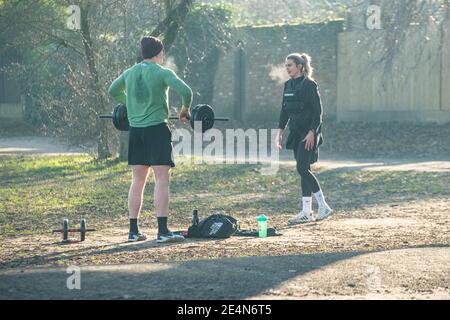 Ein Mann und eine Frau halten fit und heben Gewichte Während der Sperre in einem Londoner Park Stockfoto