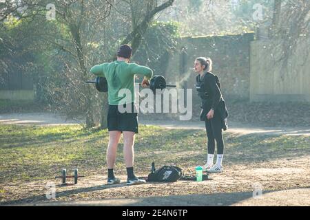 Ein Mann und eine Frau halten fit und heben Gewichte Während der Sperre in einem Londoner Park Stockfoto
