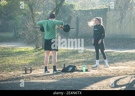 Ein Mann und eine Frau halten fit und heben Gewichte Während der Sperre in einem Londoner Park Stockfoto