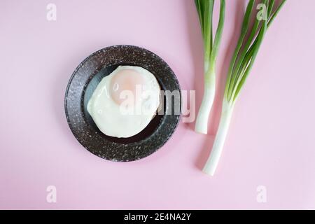 Spiegeleier und junge grüne Zwiebeln auf dem Hintergrund Stockfoto