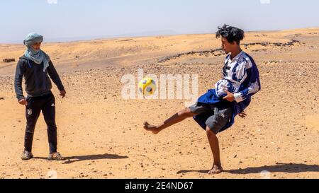 Marokkanische Kinder spielen Fußball mit einem Ball im Sommer der Sahara Wüste. Stockfoto