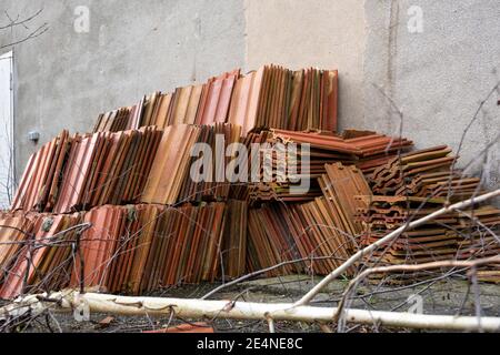 Rote Lehmdachziegel auf einer verputzten Hauswand auf einer Baustelle während der Renovierung eines alten Gebäudes gestapelt, ausgewählt Fokus Stockfoto