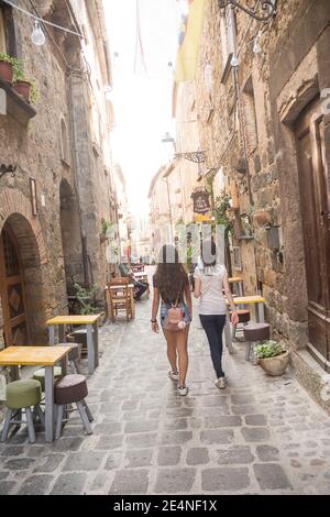 Bolsena, Italien - 20. September 2020: Zwei weibliche Touristen in der Altstadt von Bolsena unter den Tischen der Straßenrestaurants. Stockfoto