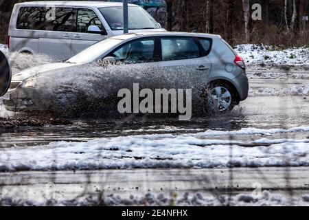 Huerth, NRW, Deutschland, 01 24 2021, ein Auto fährt durch eine Pfütze und das Wasser spritzt auf, Schnee, der langsam auftaut Stockfoto