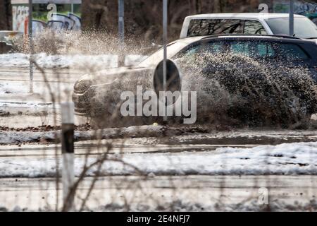 Huerth, NRW, Deutschland, 01 24 2021, ein Auto fährt durch eine Pfütze und das Wasser spritzt auf, Schnee, der langsam auftaut Stockfoto