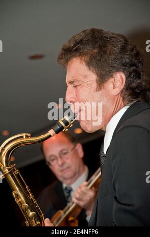 Duette mit Saxophon und Gitarre von zwei männlichen Musikern bei Eine Party Stockfoto