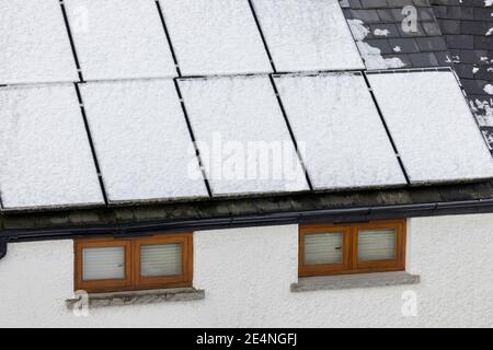 Sonnenkollektoren auf Hausdach mit Schnee bedeckt und nicht in der Lage, Strom zu erzeugen, Llanfoist, Wales, Großbritannien Stockfoto