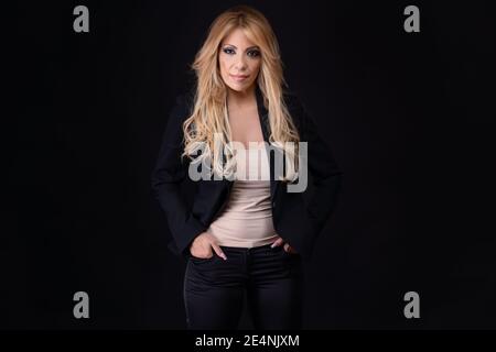 Blonde Frau, Geschäftsfrau, mittleren Alters, europäisch-Portugiesisch, posiert mit positiven Emotionen auf schwarzem Hintergrund. Stockfoto