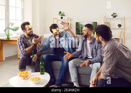 Freunde sitzen auf dem Sofa zu Hause und spielen, wer bin Ich schätze Spiel mit Post-it-Notizen Stockfoto