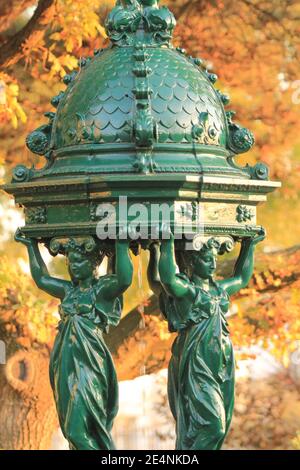 Wallace Brunnen in Paris im Herbst / einer der Trinkbrunnen in Paris im Herbst sogenannte Wallace Fontänen Mit gelbem Laub als Hintergrund Stockfoto