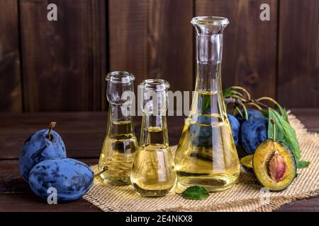Pflaumenbrand oder Schnaps in kleinen Glasflaschen mit frischen und leckeren Pflaumen auf einem Holztisch. Selektiver Fokus. Stockfoto
