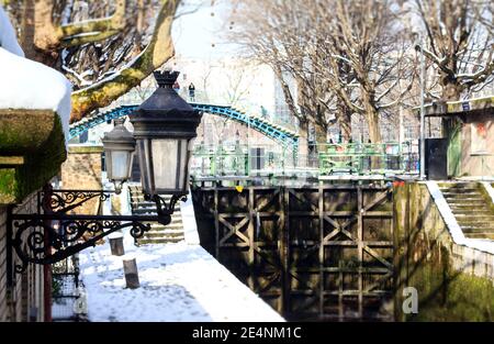 Eine der Schleusen des Canal Saint Martin in Paris im Winter, unter einer weißen Abdeckung von Neuschnee. Stockfoto