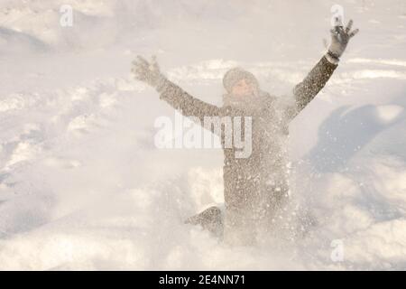 Unschärfe-Effekte wie im Kino werden durch fallende Schneeflocken eingefangen. Fröhlicher Junge, der im Winter in Schneeverwehungen spielt. Lachen und Freude Konzept Stockfoto