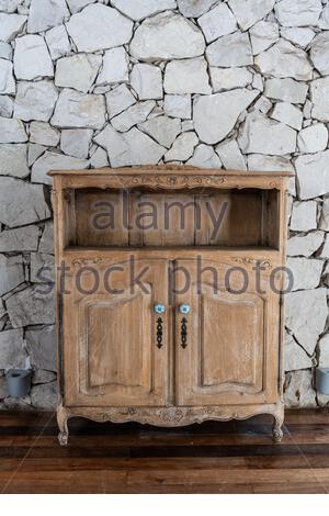 Hölzerner alter kleiner leerer Schrank über einer Steinwand Stockfoto