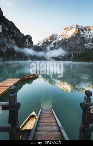 Eine vertikale Aufnahme von Holztreppen, die den See hinunter gehen Mit einem faszinierenden Blick auf die Berge im Hintergrund Stockfoto