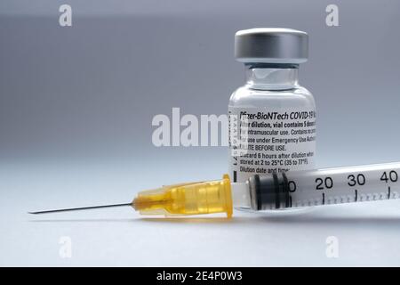 Original Pfizer BioNTech COVID-19 Impfstofffläschchen und Spritze daneben. Echtes Impffoto. Selektiver Fokus. Stafford, Vereinigtes Königreich - Januar 23 2021. Stockfoto