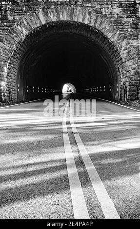 Straßenlinien führen in einen kreisförmigen Tunnel auf dem Blue Ridge Parkway in der Nähe von Asheville, NC, USA Stockfoto