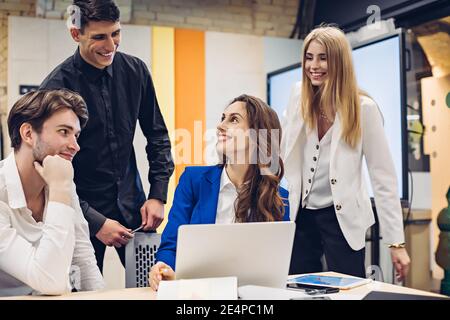 Glückliche junge Managerin, umgeben von Kollegen im Büro Stockfoto