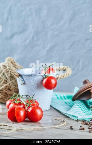 Eimer mit Tomaten und halbgeschnittenen Tomaten auf Holztisch Stockfoto