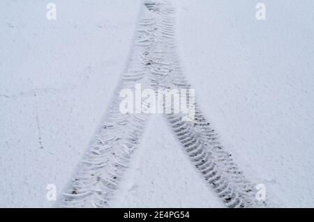 Nahaufnahme der Spuren von Autorädern in einem Straße mit Schnee bedeckt Stockfoto