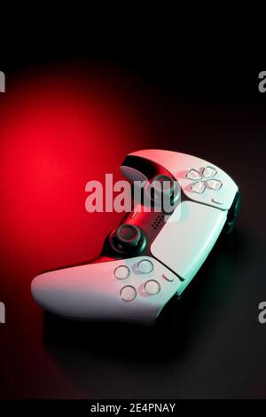 Modernes weißes Gamepad in rot und blau beleuchtet. Game Controller für Videospiele und E-Sports auf dunklem Hintergrund. Stockfoto